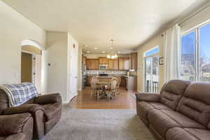 Carpeted living room featuring arched walkways, recessed lighting, an inviting chandelier, a sink, and baseboards