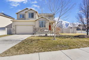 View of front of property featuring concrete driveway, fence, a mountain view, a garage, and stone siding