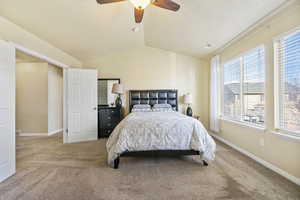 Carpeted bedroom with lofted ceiling, a ceiling fan, visible vents, and baseboards