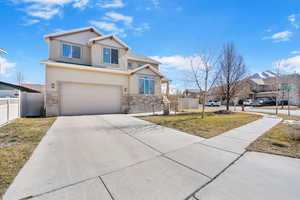 View of front of property featuring a garage, stone siding, fence, and concrete driveway