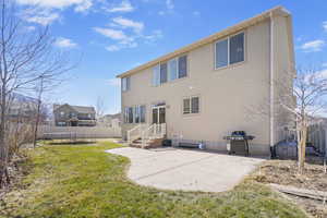 Back of house with a patio, a trampoline, fence, a yard, and stucco siding