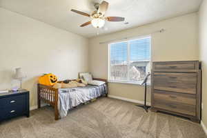 Carpeted bedroom with a ceiling fan, visible vents, and baseboards