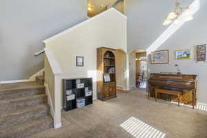 Interior space with carpet floors, arched walkways, a high ceiling, an inviting chandelier, and stairs