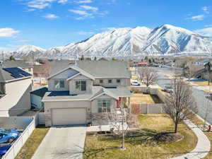 View of front facade with driveway, stone siding, an attached garage, fence private yard, and a mountain view