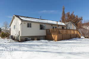 Snow covered house featuring a deck and cooling unit