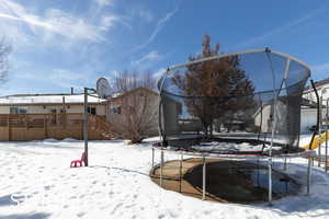 Yard layered in snow featuring a trampoline and stairway