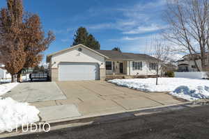 Ranch-style home featuring a garage, concrete driveway, brick siding, and fence