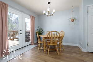 Dining area featuring an inviting chandelier, baseboards, wood finished floors, and french doors