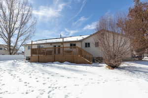 Snow covered rear of property with stairway and a deck