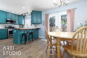 Kitchen with blue cabinets, stainless steel appliances, a peninsula, light wood-style floors, and tasteful backsplash