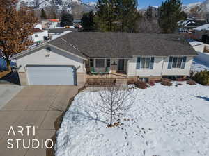 Single story home with an attached garage, a mountain view, brick siding, driveway, and roof with shingles