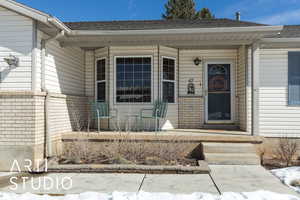 Snow covered property entrance with brick siding and roof with shingles