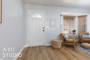 Foyer entrance with light wood-style flooring and baseboards