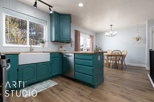 Kitchen featuring a chandelier, a sink, hanging light fixtures, dishwasher, and dark wood finished floors