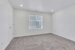 Empty room featuring light carpet, recessed lighting, visible vents, and baseboards