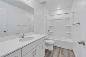 Bathroom featuring visible vents, toilet, shower / tub combination, wood finished floors, and vanity