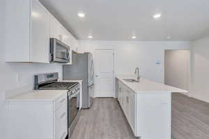 Kitchen featuring light countertops, appliances with stainless steel finishes, a sink, and white cabinets