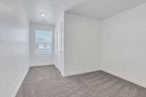 Carpeted spare room featuring baseboards and visible vents