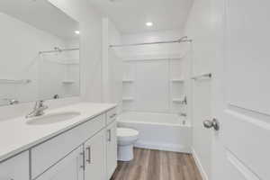 Bathroom with bathing tub / shower combination, vanity, toilet, and wood finished floors