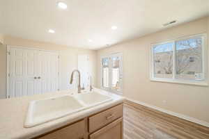 Kitchen with plenty of natural light, light countertops, large double sink, new windows.