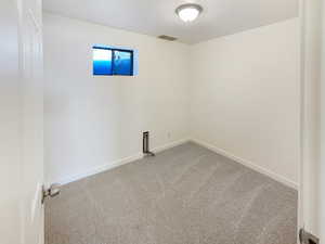 Spare room featuring carpet floors, visible vents, and baseboards