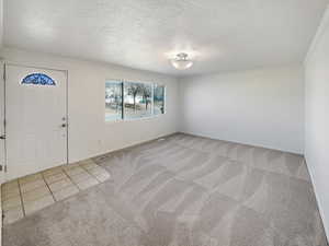 Foyer entrance featuring light carpet, crown molding, and a textured ceiling