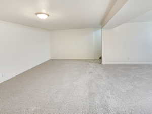 Carpeted spare room featuring baseboards