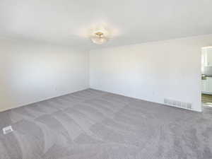 Spare room featuring a textured ceiling, carpet floors, visible vents, and crown molding