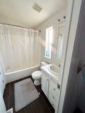 Full bathroom with wood finish floors, visible vents, shower / bathtub combination with curtain, toilet, and vanity