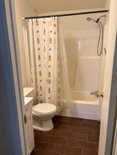 Full bath with toilet, wood tiled floor, shower / tub combo with curtain, and vanity