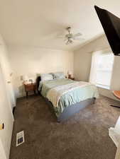 Bedroom with dark colored carpet, visible vents, and ceiling fan