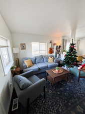 Living area featuring visible vents, vaulted ceiling, and carpet flooring