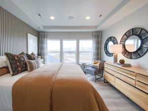 Bedroom featuring light wood-type flooring, a raised ceiling, and recessed lighting