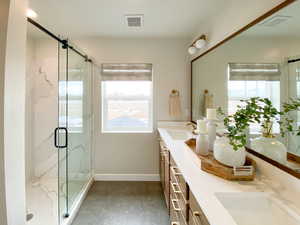 Bathroom featuring a marble finish shower and double vanity