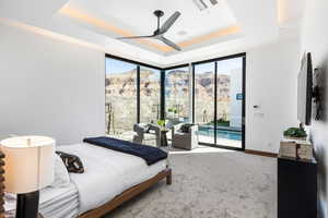 Carpeted bedroom featuring access to exterior, visible vents, multiple windows, and a tray ceiling