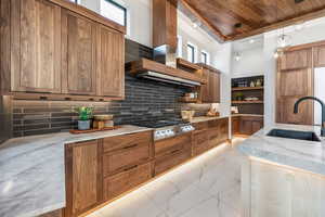 Kitchen featuring hanging light fixtures, marble finish floor, brown cabinets, and a sink