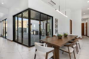 Dining space with recessed lighting, a high ceiling, visible vents, baseboards, and marble finish floor