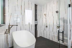 Bathroom with a soaking tub, tile walls, and a marble finish shower