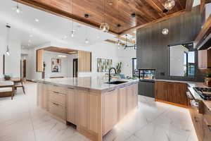 Kitchen with wooden ceiling, a spacious island, decorative light fixtures, marble finish floor, and a sink