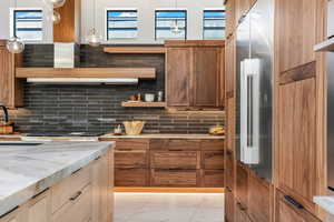 Kitchen featuring hanging light fixtures, marble finish floor, open shelves, and backsplash