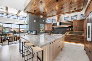 Kitchen with marble finish floor, an island with sink, a sink, and pendant lighting