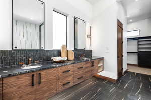 Full bathroom with a sink, baseboards, double vanity, tasteful backsplash, and a walk in closet