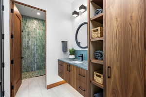 Full bath with vanity, baseboards, walk in shower, and tile patterned floors