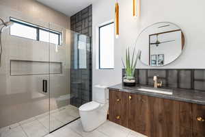 Bathroom featuring toilet, a stall shower, tile patterned floors, and vanity