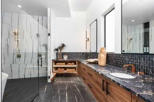 Full bath with a sink, marble finish floor, backsplash, a marble finish shower, and double vanity