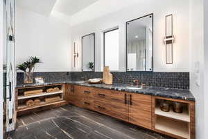 Bathroom featuring marble finish floor, a sink, backsplash, and double vanity