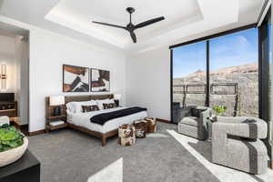 Bedroom with carpet floors, a tray ceiling, a mountain view, and baseboards