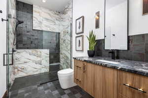 Bathroom with toilet, tasteful backsplash, a shower stall, and vanity