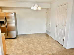 Unfurnished dining area featuring baseboards, ornamental molding, and a notable chandelier