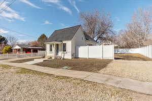 Bungalow with a shingled roof, a fenced front yard, and stucco siding